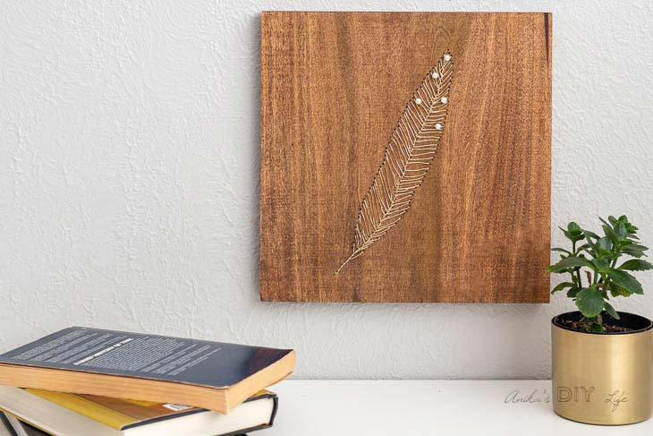 feather made from pins and wire on a wood square