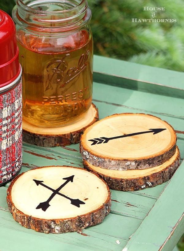 A rustic wood slice DIY coaster that features a simple black arrow design painted on the surface.