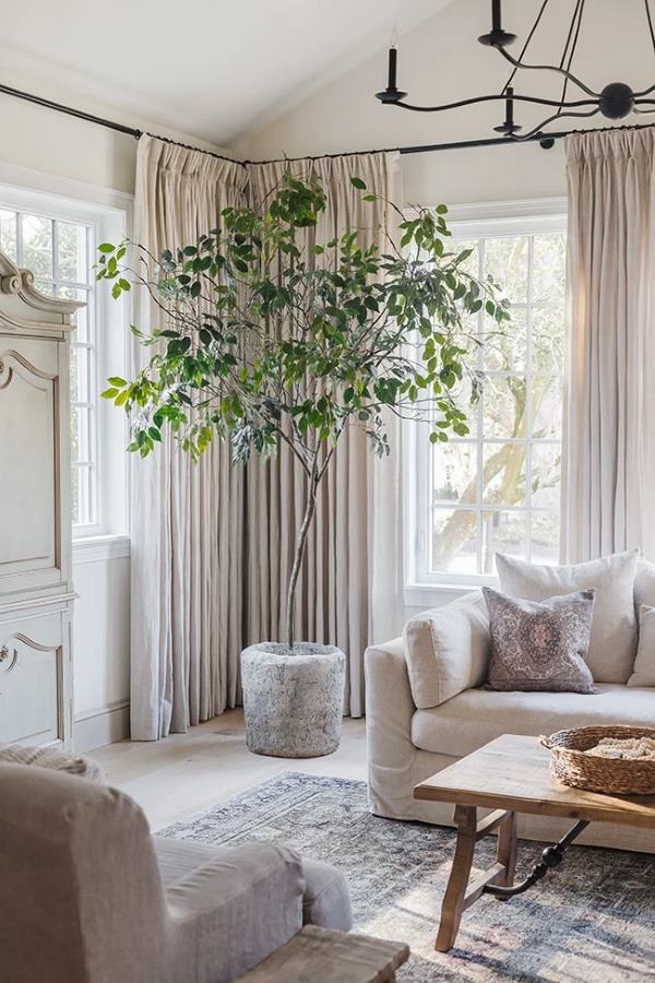 Faux indoor tree made from real branches styled in a neutral living room corner