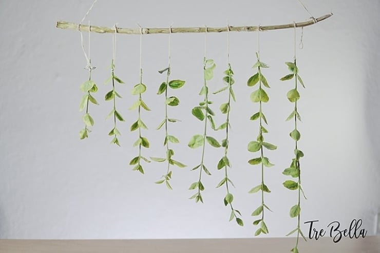 Hanging branch backdrop with cascading greenery strands suspended from a natural tree branch