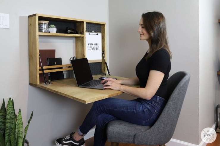 Wall-mounted fold-down desk with shelves creating a small home office workspace in a tight corner