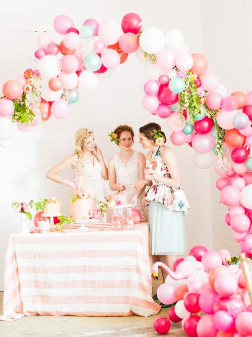 women at a birthday party standing underneath a balloon arch
