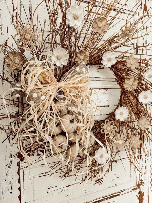 Neutral fall wreath with dried flowers, branches, and a large raffia bow