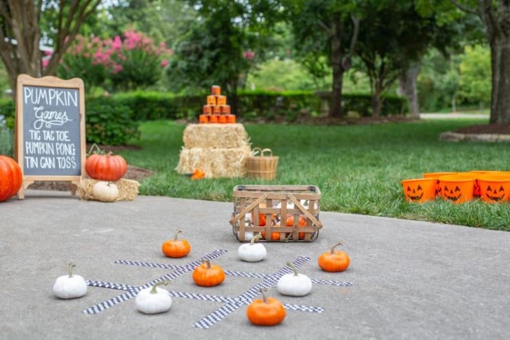 Outdoor pumpkin tic-tac-toe and carnival-style games set up with hay bales and buckets