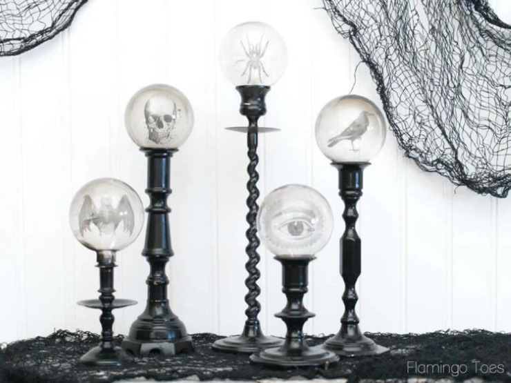 Black candlesticks with crystal balls featuring eerie images like bats, skulls, and an eye