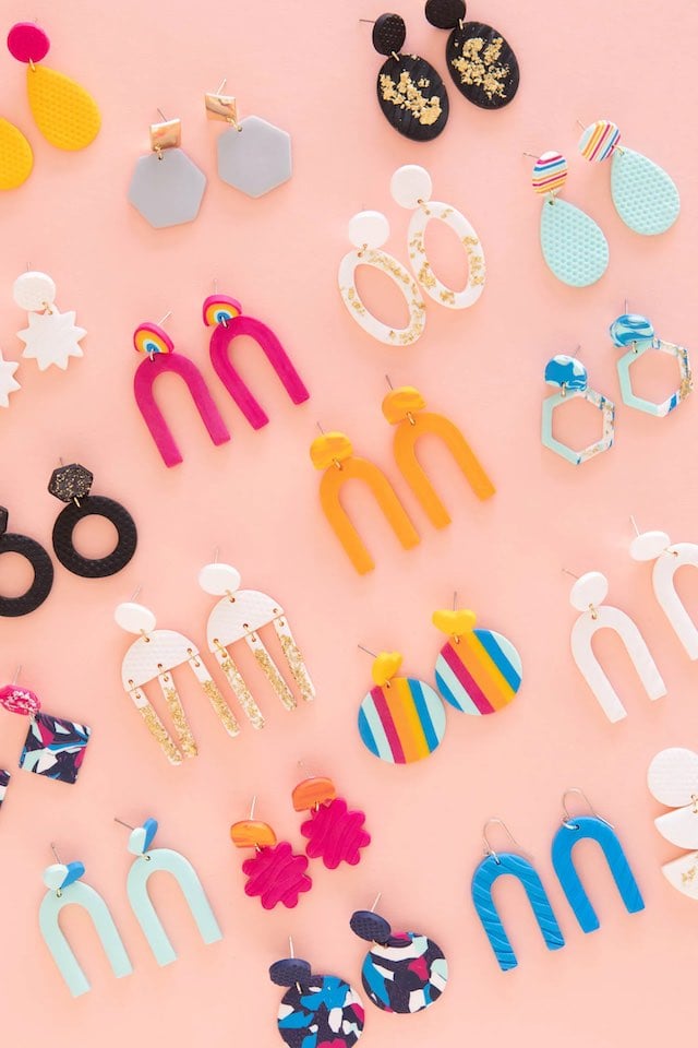 A variety of colorful DIY clay earrings on a peach background