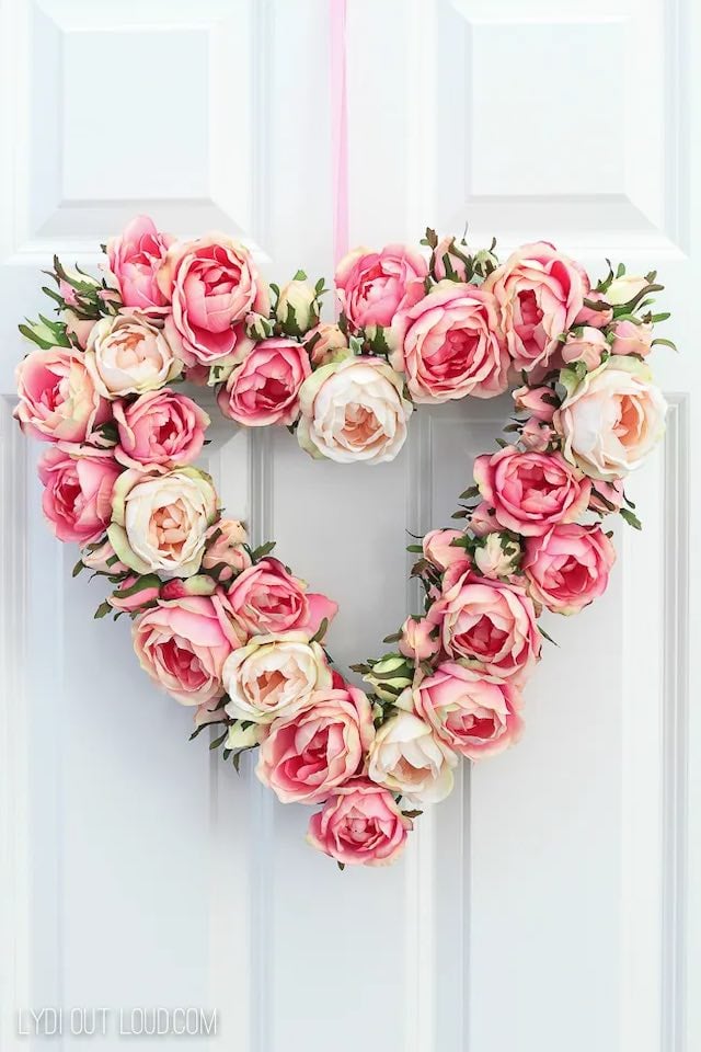 A heart shaped wreath made of pink and cream colored flowers