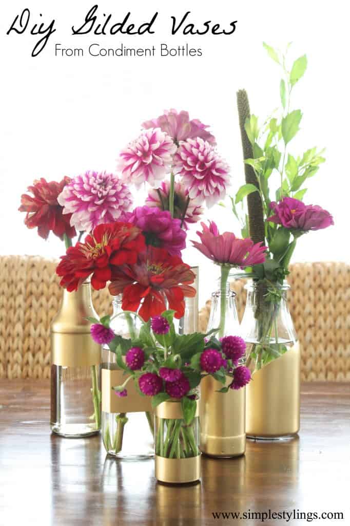 clear glass bottles partially painted gold holding a variety of flowers