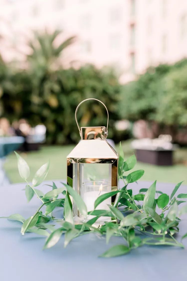 golden lantern surrounded by simple greenery on a table