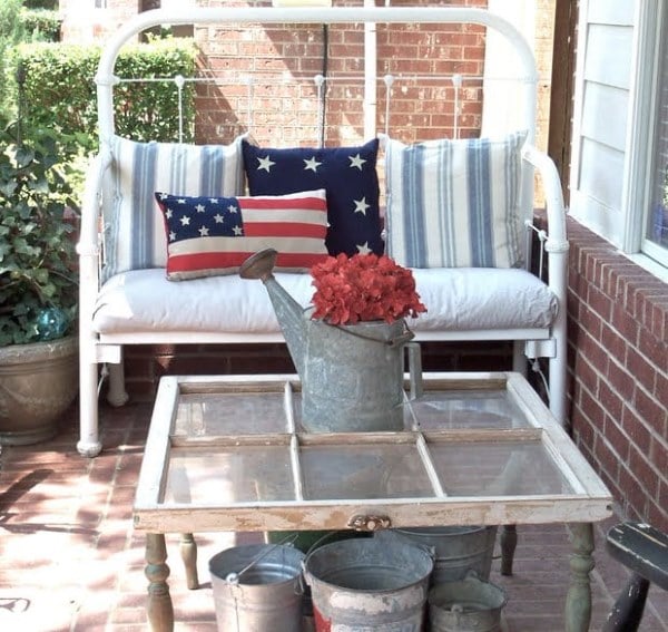 Front porch with flag themed pillow and red flowers