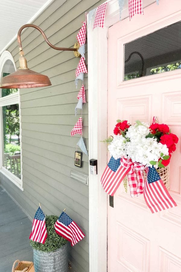 Flower wreath with flags in it hanging on pink front door