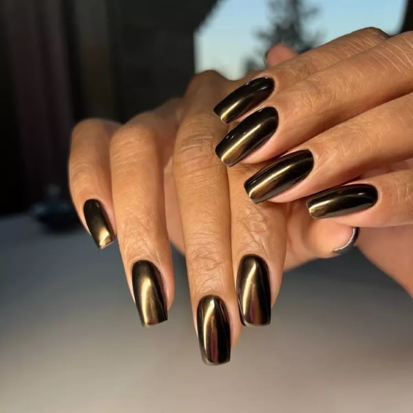 Long almond-shaped nails in a rich chocolate-gold chrome with a shiny metallic finish.