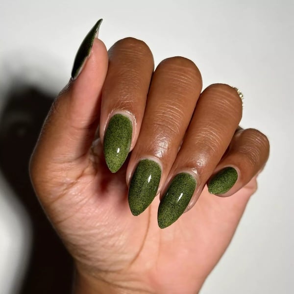 Almond-shaped nails in a playful Grinch-green shade with a soft speckled texture.