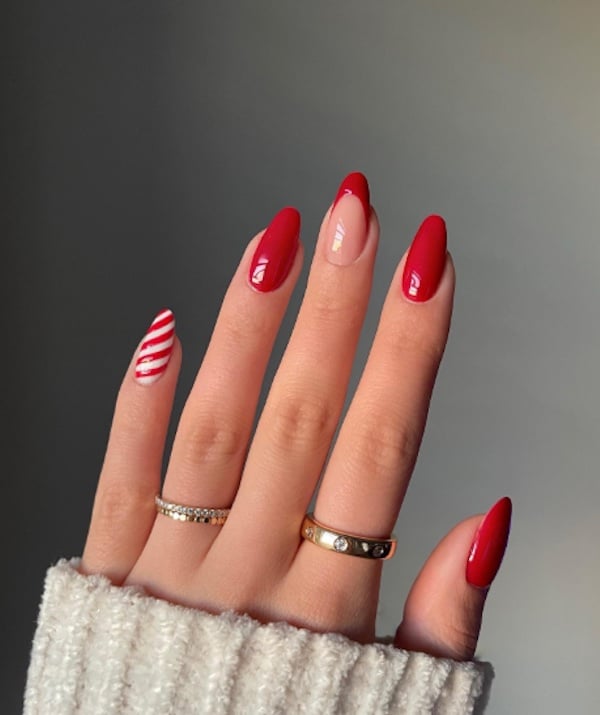 Bright red nails with a candy cane accent nail and a red french tip accent nail