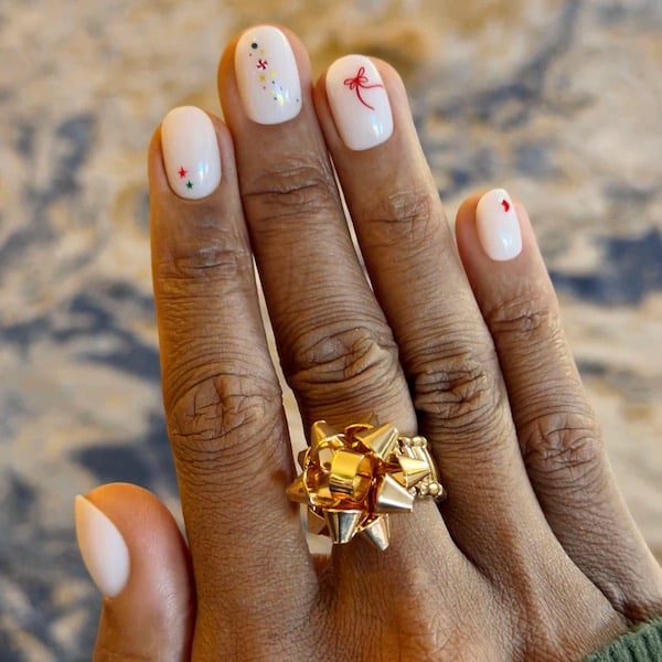 sheer pink nails with tiny Christmas themed art on each nail