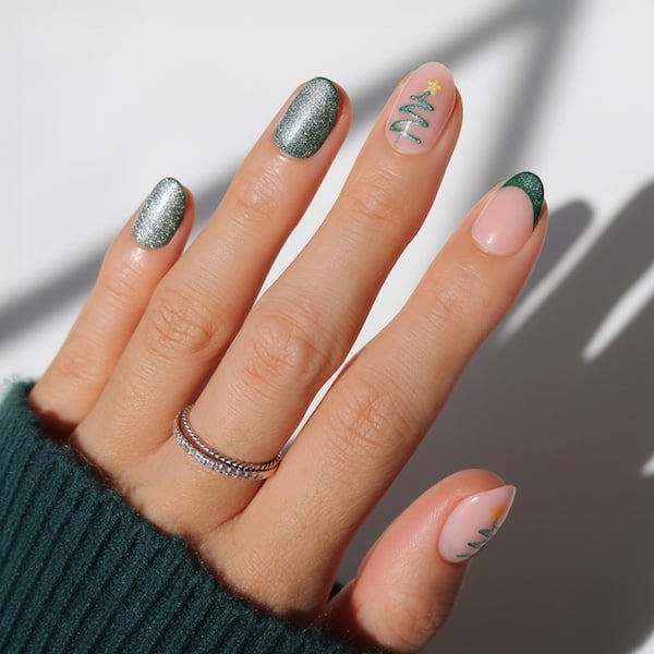 short nails featuring solid shimmery green and accent nails with sheer pink with green tips, and sheer pink with a tiny christmas tree design