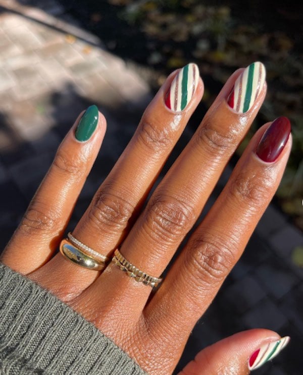 deep red and green nails with white, green, red, and gold striped accent nails painted to look like wrapping paper