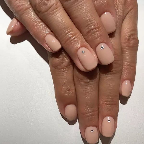 sheer nude painted nails with single rhinestones near base of nail