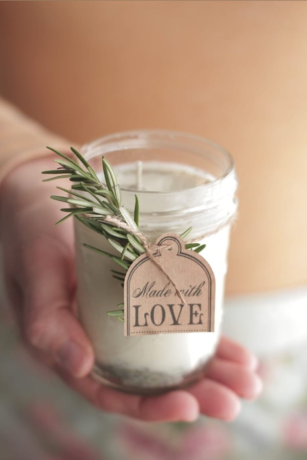 simple white diy candle in a mason jar tied with rosemary and a gift tag