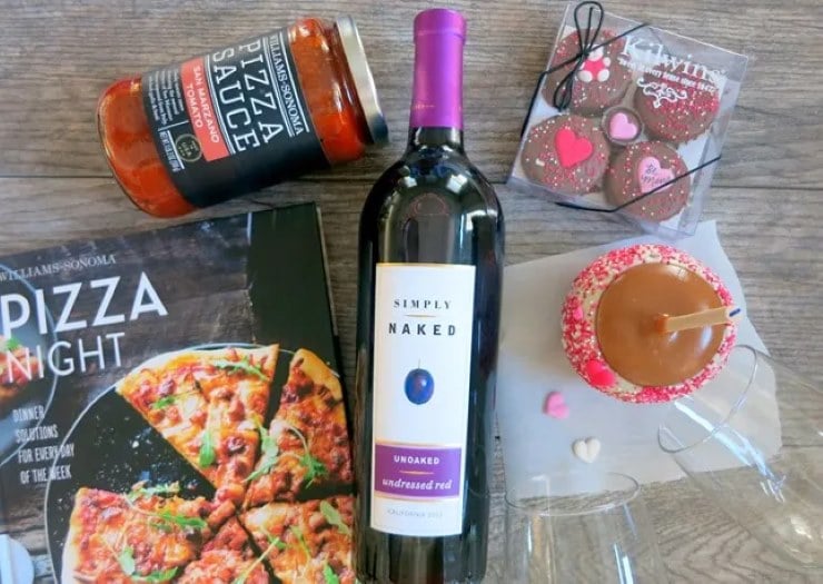 Date night gift basket with wine, pizza night cookbook, sauce, desserts, and Valentine themed treats