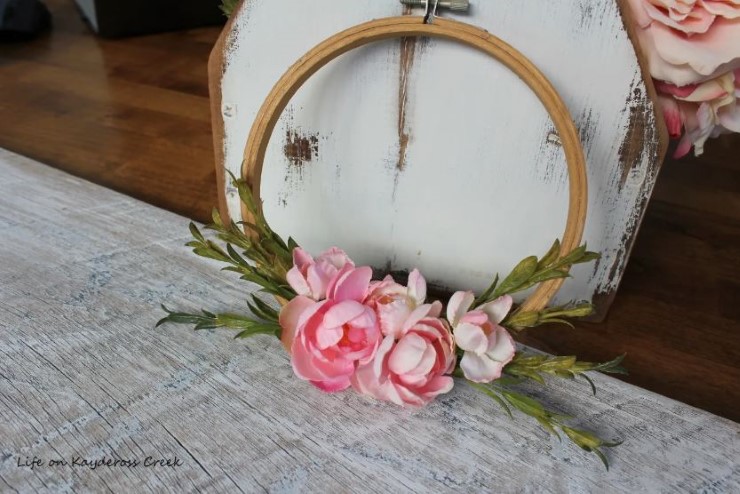 Minimal embroidery hoop spring wreath with pink faux flowers on a rustic surface