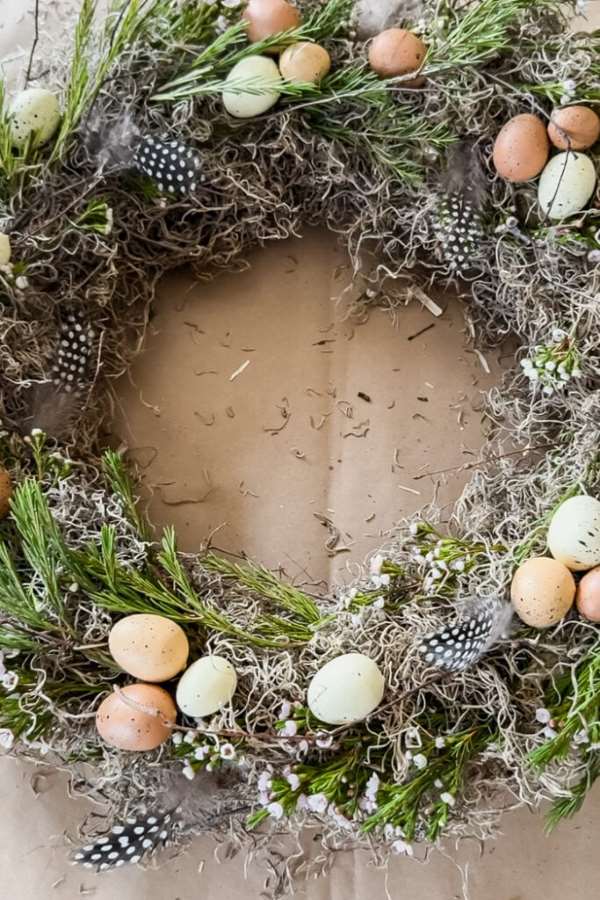 Light and airy spring wreath with greenery, feathers, and soft floral accents