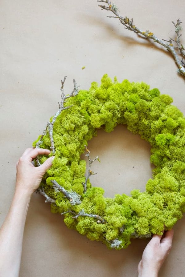 Bright green moss spring wreath with natural branches on a neutral background