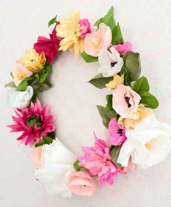 Colorful paper flower spring wreath with pink, white, and yellow blooms on a neutral background