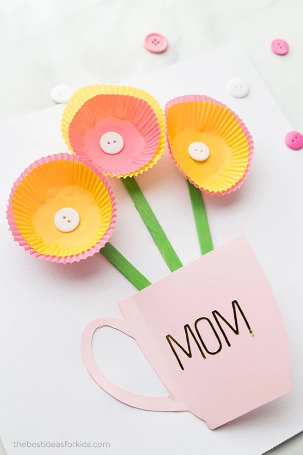 Mother's Day card with cupcake liner flowers in pastel colors inside a pink mug labeled “Mom”.