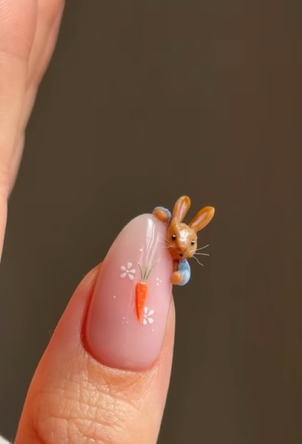 Close-up of a detailed 3D bunny nail art with a carrot design on a soft pink manicure.