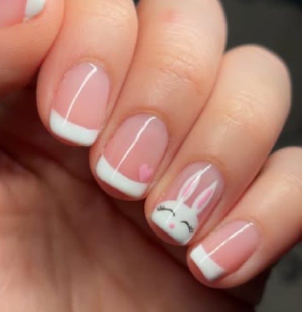 Classic French nails with a cute bunny face and a little pink heart for Easter nail art.