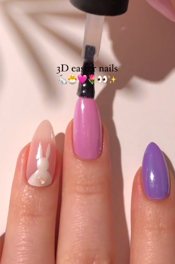 3D bunny tail nail art with shiny pastel pink and purple Easter manicure.