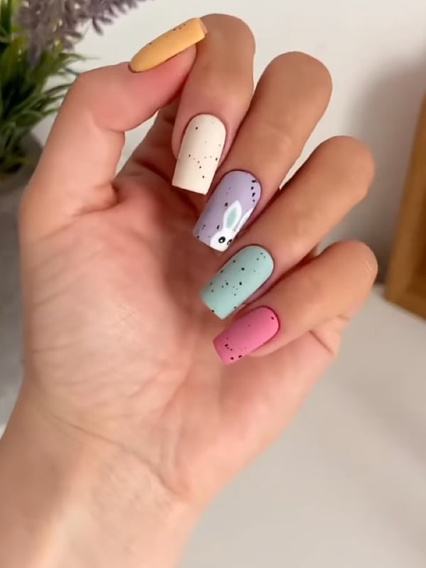 Colorful pastel nails with a little bunny accent inspired by Easter egg designs.
