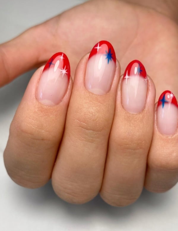 Red French tip nails with tiny blue and white firework star details on nude base