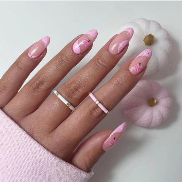 Pink French tip nails with tiny pink pumpkins, small black dots, and pink and white decorative accents.